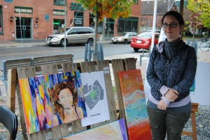 Artist Cynthia Münster stands next to her paintings at the Support Local pop-up gallery, Oct. 18, 2014. [Photo ©Lesley LeRoux]