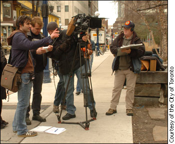 With the help of a cameraman, a director sets up his shot on a Toronto street