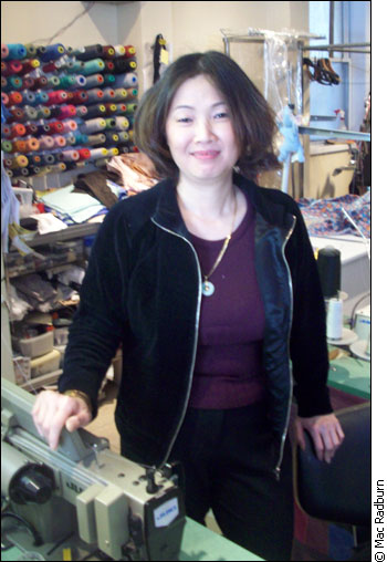 Lang Chi Dang stands with her sewing machine.