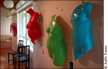 Coloured casts of torsos hanging on a wall.