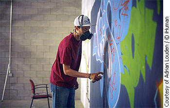 Adrian Louden is spray painting on a wall