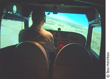 Jon Wade flies a plane simulator. There are green fields on the screen.
