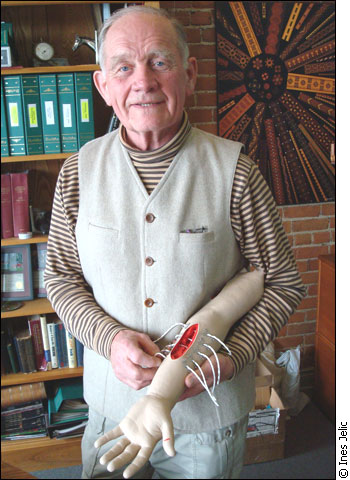 Leonard Lee is holding a rubber arm demonstrating the use of the wound closure system