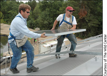 Two men install a solar panel on a roof