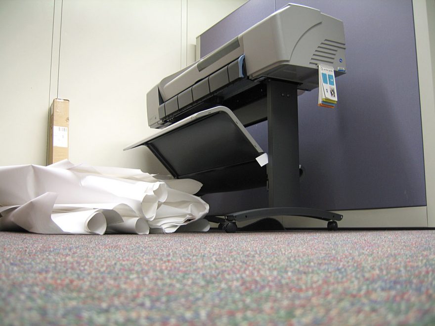 a printer with paper on the floor